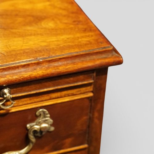 fig 4. A 19th-century small mahogany chest of drawers featuring four graduated drawers with brass swan-neck handles, a pull-out brushing slide, and bracket feet.