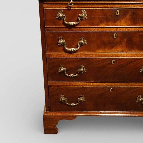 fig 5. A 19th-century small mahogany chest of drawers featuring four graduated drawers with brass swan-neck handles, a pull-out brushing slide, and bracket feet.