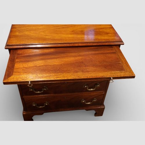 fig 7. A 19th-century small mahogany chest of drawers featuring four graduated drawers with brass swan-neck handles, a pull-out brushing slide, and bracket feet.