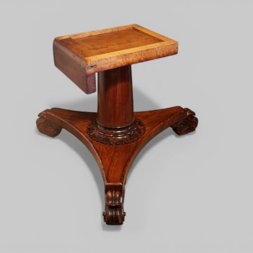 fig 4. A circular antique rosewood dining table with a highly figured timber top shown upright above a carved tri-form pedestal base.