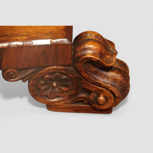 fig 5. A circular antique rosewood dining table with a highly figured timber top shown upright above a carved tri-form pedestal base.