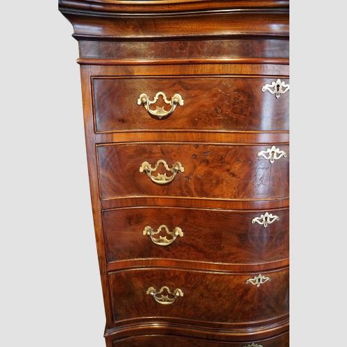 fig 3. A tall George V walnut serpentine front tallboy chest featuring multiple drawers with decorative brass drop handles.