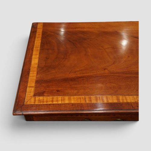 fig 1. A George III mahogany chest featuring four graduated drawers decorated with satinwood banding, brass swan-neck handles, and shaped bracket feet.