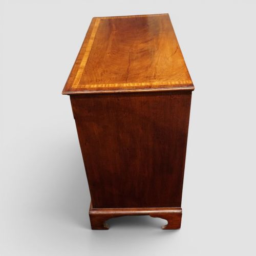 fig 2. A George III mahogany chest featuring four graduated drawers decorated with satinwood banding, brass swan-neck handles, and shaped bracket feet.