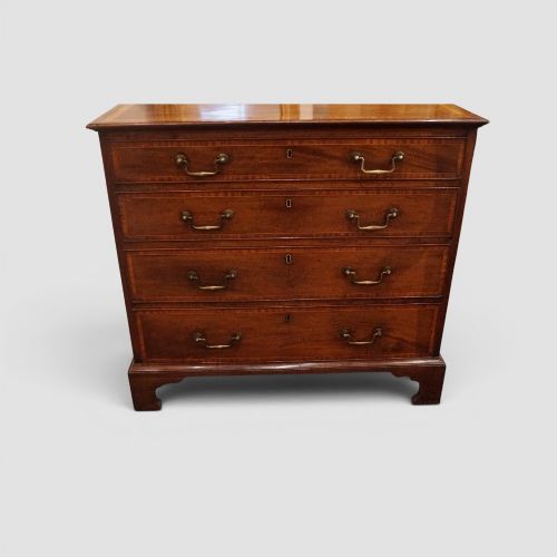 fig 3. A George III mahogany chest featuring four graduated drawers decorated with satinwood banding, brass swan-neck handles, and shaped bracket feet.