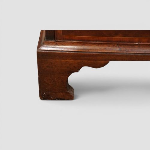 fig 5. A George III mahogany chest featuring four graduated drawers decorated with satinwood banding, brass swan-neck handles, and shaped bracket feet.