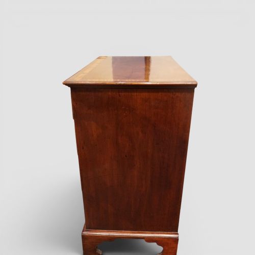 fig 6. A George III mahogany chest featuring four graduated drawers decorated with satinwood banding, brass swan-neck handles, and shaped bracket feet.