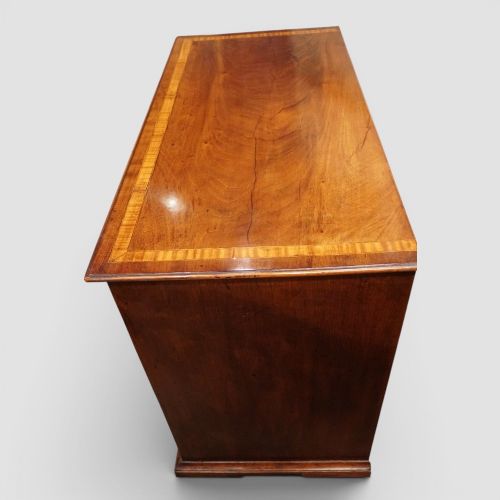 fig 7. A George III mahogany chest featuring four graduated drawers decorated with satinwood banding, brass swan-neck handles, and shaped bracket feet.