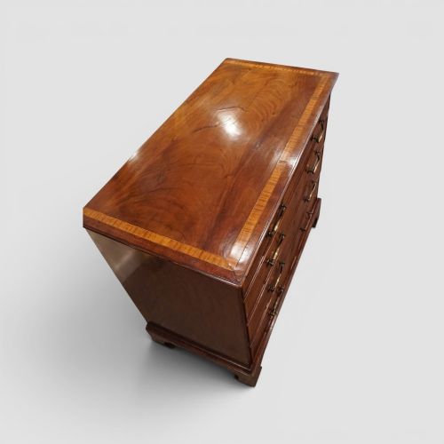 fig 8. A George III mahogany chest featuring four graduated drawers decorated with satinwood banding, brass swan-neck handles, and shaped bracket feet.