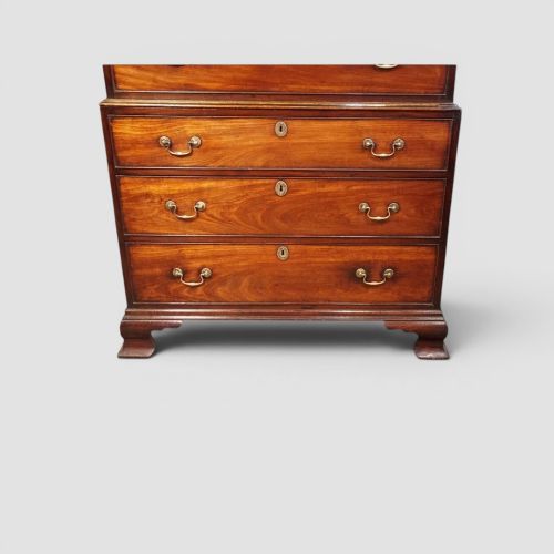 fig 2. A tall George III mahogany chest-on-chest featuring a carved blind fretwork cornice, brass swan-neck handles, and bracket feet.