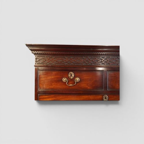 fig 4. A tall George III mahogany chest-on-chest featuring a carved blind fretwork cornice, brass swan-neck handles, and bracket feet.