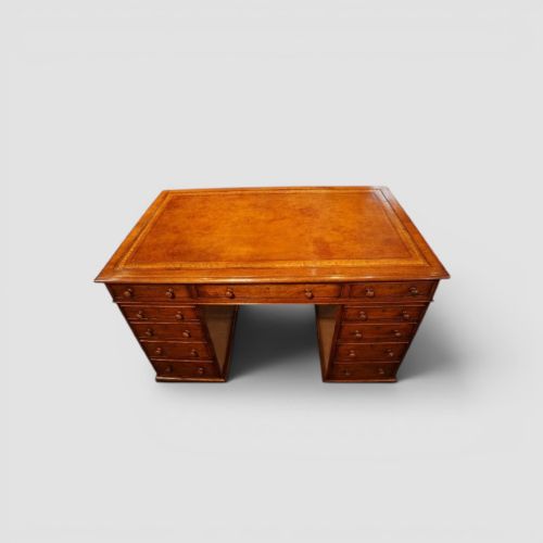 fig 5. A Victorian mahogany partners desk featuring a tooled leather writing surface, twin pedestals, and an eleven-drawer front configuration with turned wooden knobs.