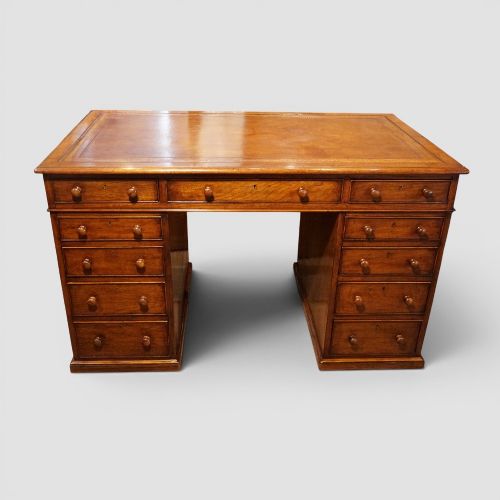 fig 6. A Victorian mahogany partners desk featuring a tooled leather writing surface, twin pedestals, and an eleven-drawer front configuration with turned wooden knobs.