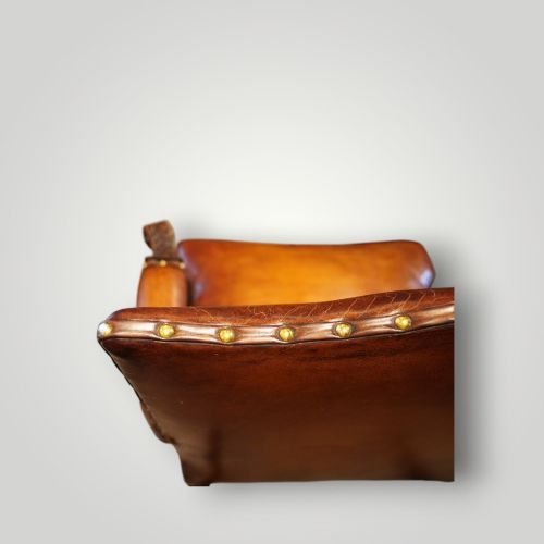 fig 5. A Georgian style Gainsborough armchair upholstered in warm tan leather with brass stud detailing and carved mahogany legs.
