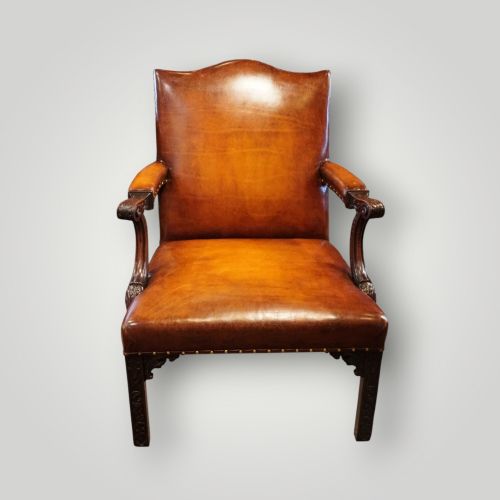 fig 8. A Georgian style Gainsborough armchair upholstered in warm tan leather with brass stud detailing and carved mahogany legs.