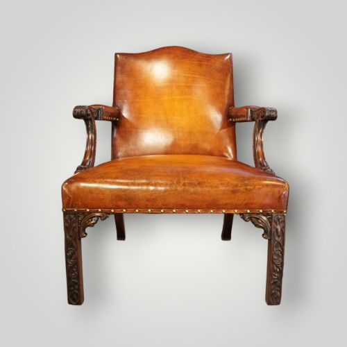 fig 12. A Georgian style Gainsborough armchair upholstered in warm tan leather with brass stud detailing and carved mahogany legs.