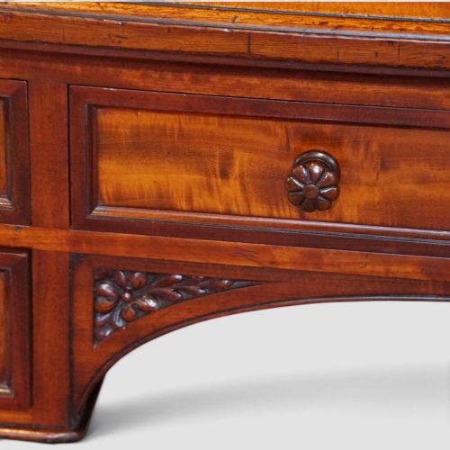 fig 2. Victorian mahogany writing table featuring a dark green leather top, five drawers with circular wooden handles, turned legs, and brass castors.