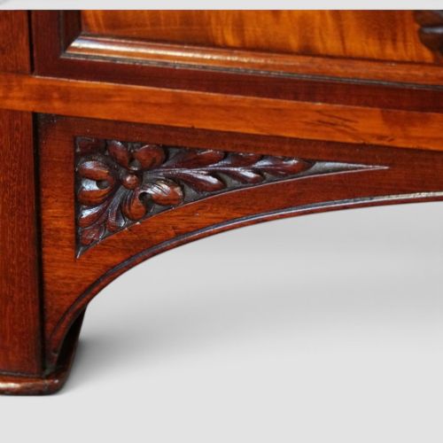 fig 6. Victorian mahogany writing table featuring a dark green leather top, five drawers with circular wooden handles, turned legs, and brass castors.