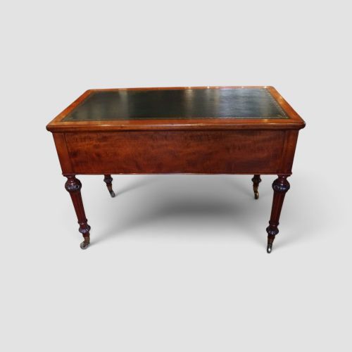 Victorian mahogany writing table featuring a dark green leather top, five drawers with circular wooden handles, turned legs, and brass castors. View XIII