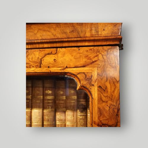 fig 10. A George I walnut bureau bookcase featuring glazed upper doors housing books, a slant-front writing flap, and lower drawers with brass drop handles.