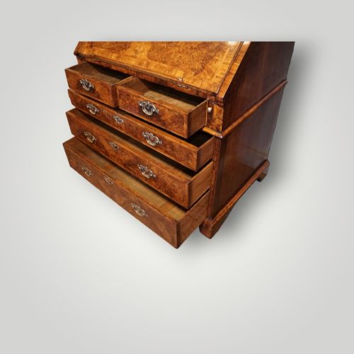 fig 11. A George I walnut bureau bookcase featuring glazed upper doors housing books, a slant-front writing flap, and lower drawers with brass drop handles.
