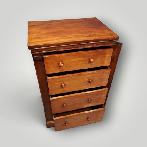 fig 3. A Victorian warm brown mahogany Wellington chest featuring four stacked drawers with turned wooden handles and a side locking bar.