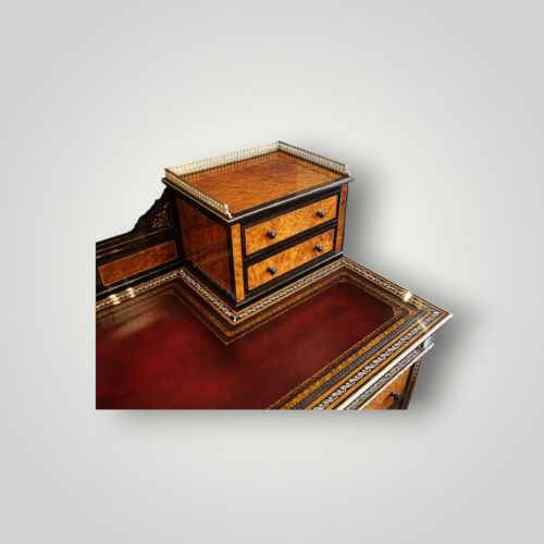 fig 1. A Victorian ebonised and thuya wood pedestal desk featuring a leather writing surface, raised side drawers, ivory inlay, and ceramic plaque details.