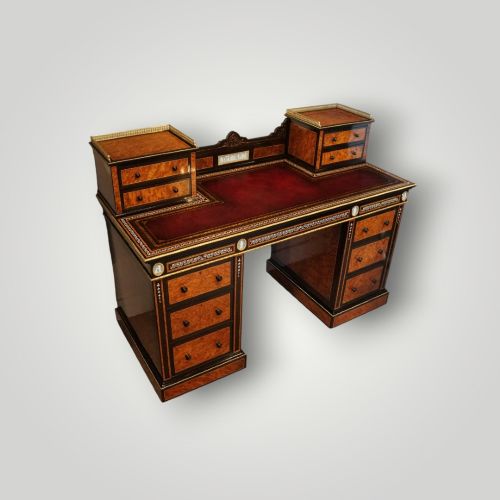 fig 2. A Victorian ebonised and thuya wood pedestal desk featuring a leather writing surface, raised side drawers, ivory inlay, and ceramic plaque details.