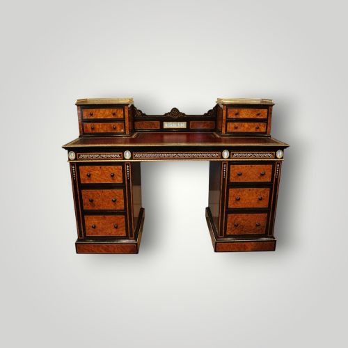 fig 4. A Victorian ebonised and thuya wood pedestal desk featuring a leather writing surface, raised side drawers, ivory inlay, and ceramic plaque details.