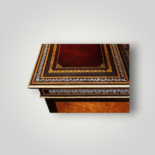 fig 7. A Victorian ebonised and thuya wood pedestal desk featuring a leather writing surface, raised side drawers, ivory inlay, and ceramic plaque details.