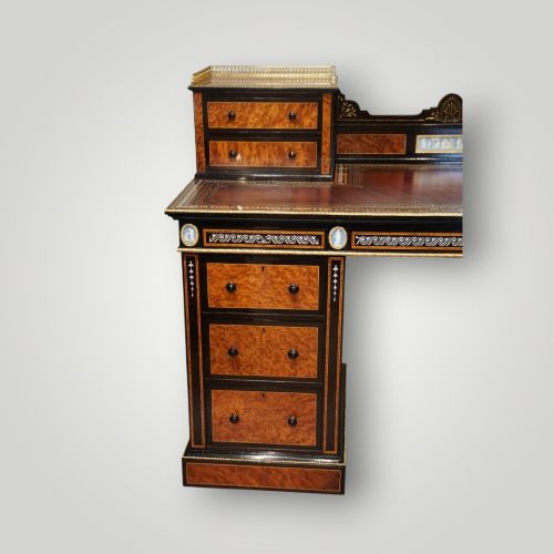 fig 9. A Victorian ebonised and thuya wood pedestal desk featuring a leather writing surface, raised side drawers, ivory inlay, and ceramic plaque details.