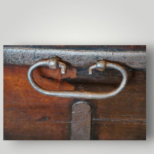 fig 1. A rectangular antique walnut wood trunk featuring heavy iron binding straps, metal corner hardware, and a brass plaque on the lid.