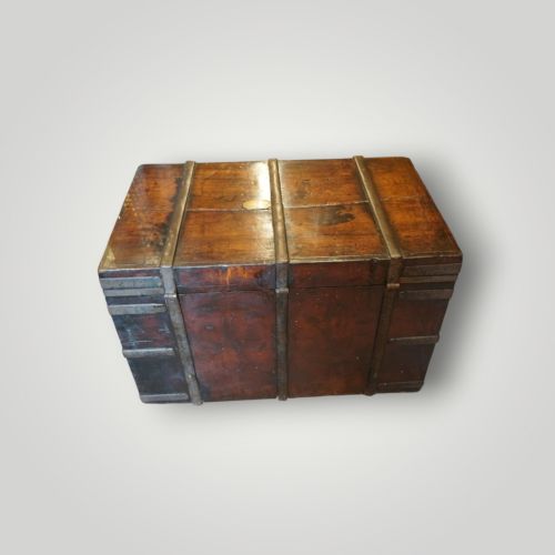 fig 8. A rectangular antique walnut wood trunk featuring heavy iron binding straps, metal corner hardware, and a brass plaque on the lid.