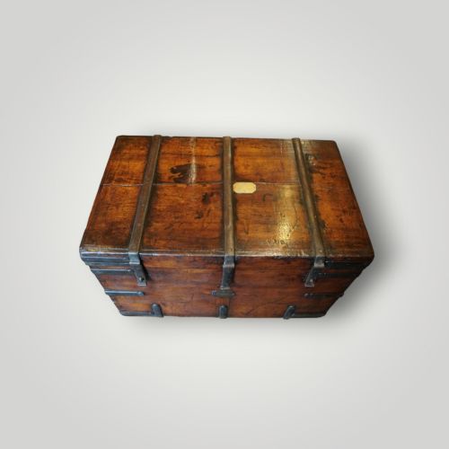 fig 10. A rectangular antique walnut wood trunk featuring heavy iron binding straps, metal corner hardware, and a brass plaque on the lid.