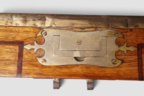 fig 5. A rectangular Victorian camphor wood campaign chest featuring polished brass binding along the edges, geometric dark line inlay, and a central brass lock escutcheon.
