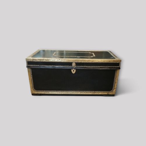 fig 1. An antique dark green leather trunk featuring brass corner straps, close-studded brass borders, and a brass keyhole escutcheon.