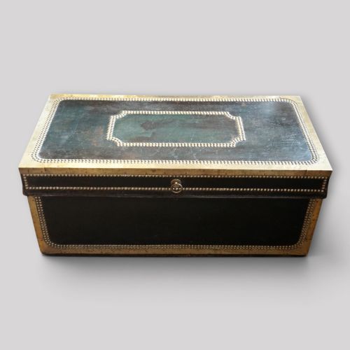 fig 2. An antique dark green leather trunk featuring brass corner straps, close-studded brass borders, and a brass keyhole escutcheon.