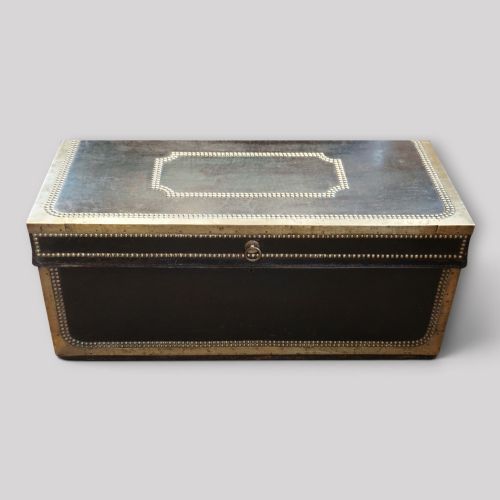 fig 4. An antique dark green leather trunk featuring brass corner straps, close-studded brass borders, and a brass keyhole escutcheon.