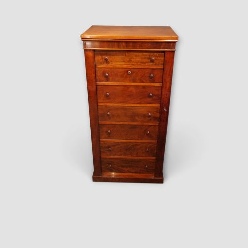 fig 1. A tall Victorian mahogany Wellington chest featuring seven drawer fronts, turned wooden knobs, and a right-hand side locking flap.