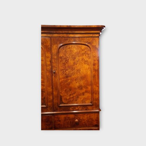 fig 4. A 19th-century Victorian burr walnut linen press featuring an upper cabinet with arched panel doors over a chest of four drawers with turned wooden knobs.