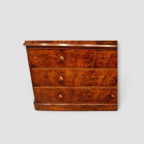 fig 5. A 19th-century Victorian burr walnut linen press featuring an upper cabinet with arched panel doors over a chest of four drawers with turned wooden knobs.
