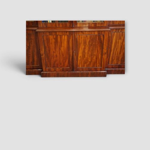 fig 2. A 19th-century mahogany breakfront bookcase featuring glazed upper doors filled with books above solid panelled cupboard doors.