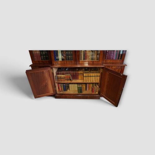fig 3. A 19th-century mahogany breakfront bookcase featuring glazed upper doors filled with books above solid panelled cupboard doors.