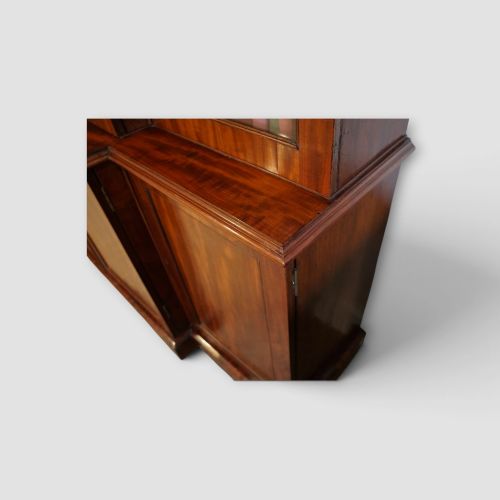 fig 4. A 19th-century mahogany breakfront bookcase featuring glazed upper doors filled with books above solid panelled cupboard doors.