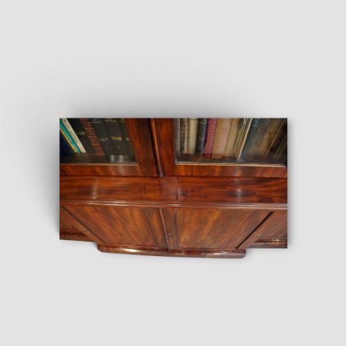 fig 7. A 19th-century mahogany breakfront bookcase featuring glazed upper doors filled with books above solid panelled cupboard doors.