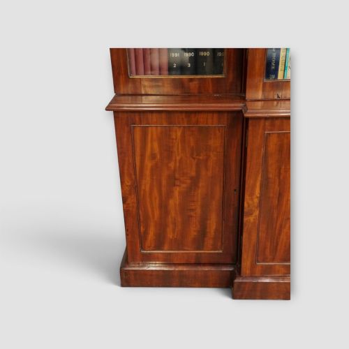 fig 8. A 19th-century mahogany breakfront bookcase featuring glazed upper doors filled with books above solid panelled cupboard doors.