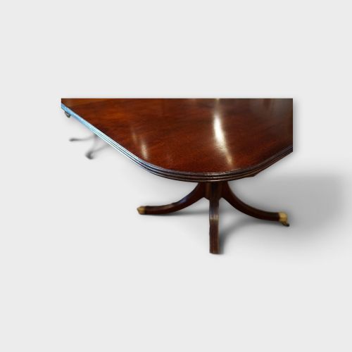fig 8. A Georgian style dark mahogany dining table featuring an extendable top, twin turned pedestal pillars, and splayed quadruped legs with brass toe caps.