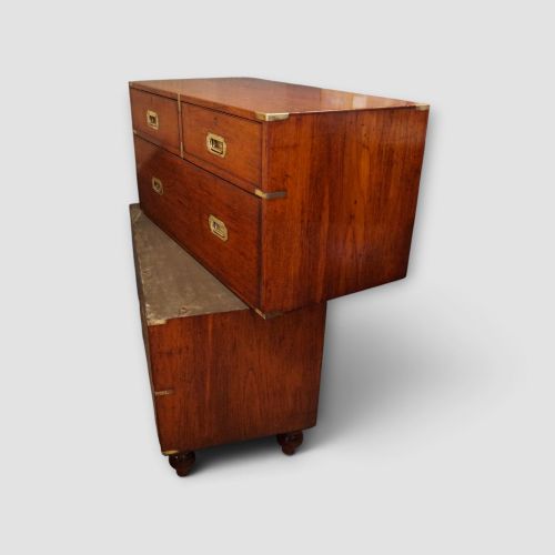 fig 7. A Victorian teak two-part military campaign chest of drawers featuring flush brass handles, brass corner mounts, and turned feet.