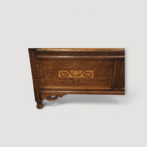 fig 4. An Art Nouveau solid oak settle featuring decorative marquetry inlay across the backrest and lower front panels, curved armrests, and a lift-up storage seat.