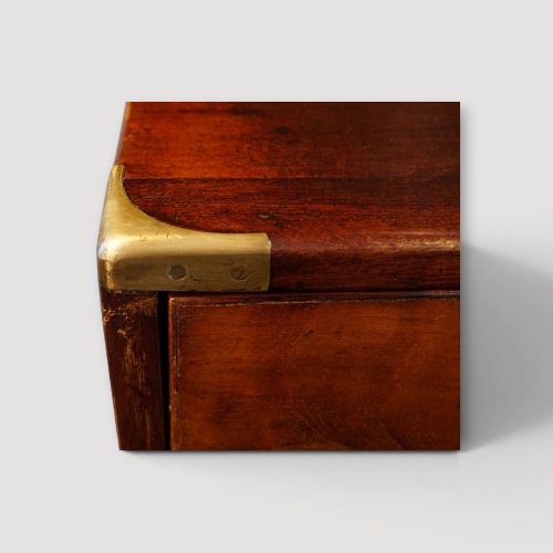 fig 7. A Victorian mahogany campaign chest featuring two short drawers over three long drawers with flush brass handles, brass corner brackets, and turned feet.